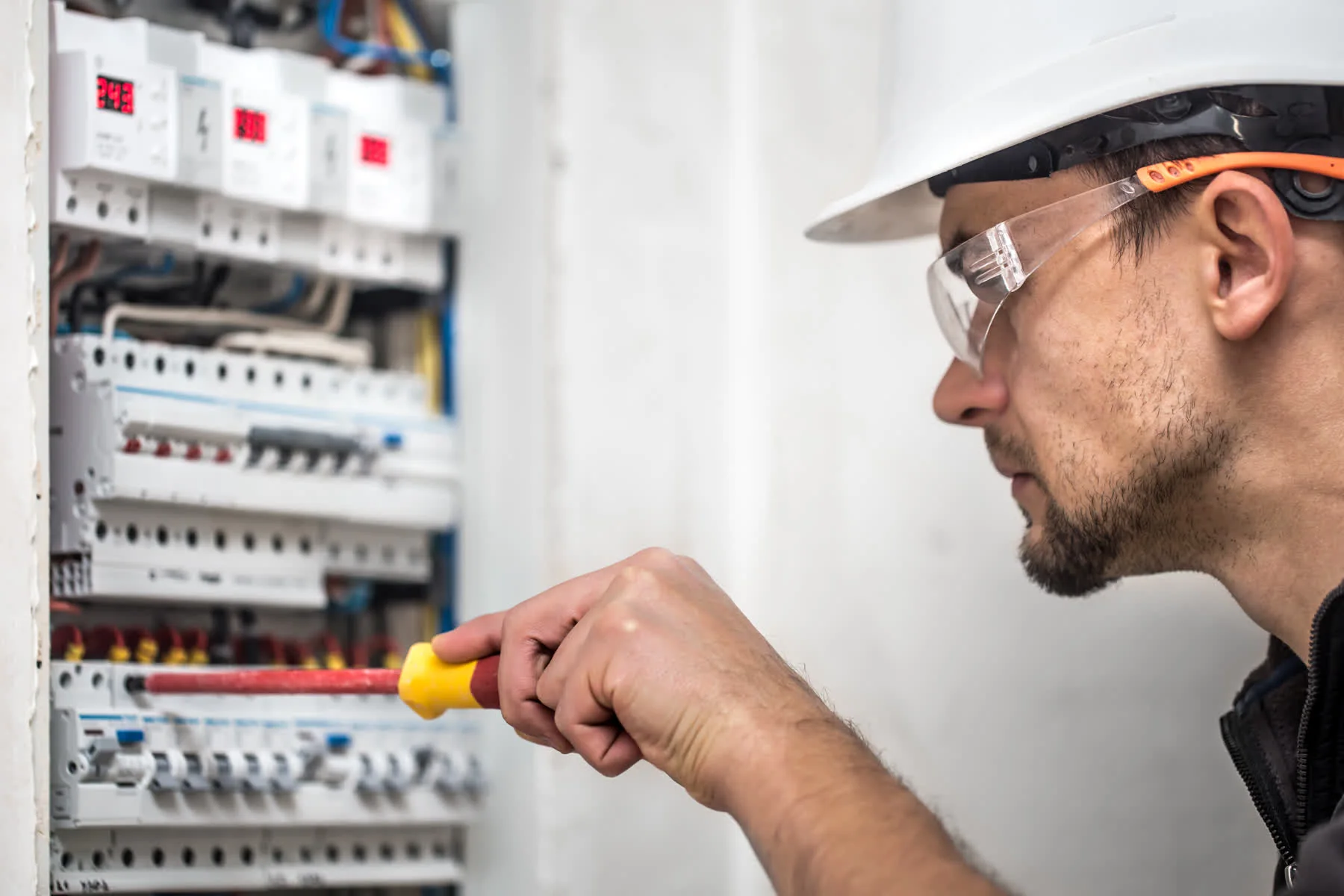 Électricien contrôlant un tableau électrique résidentiel avec un multimètre