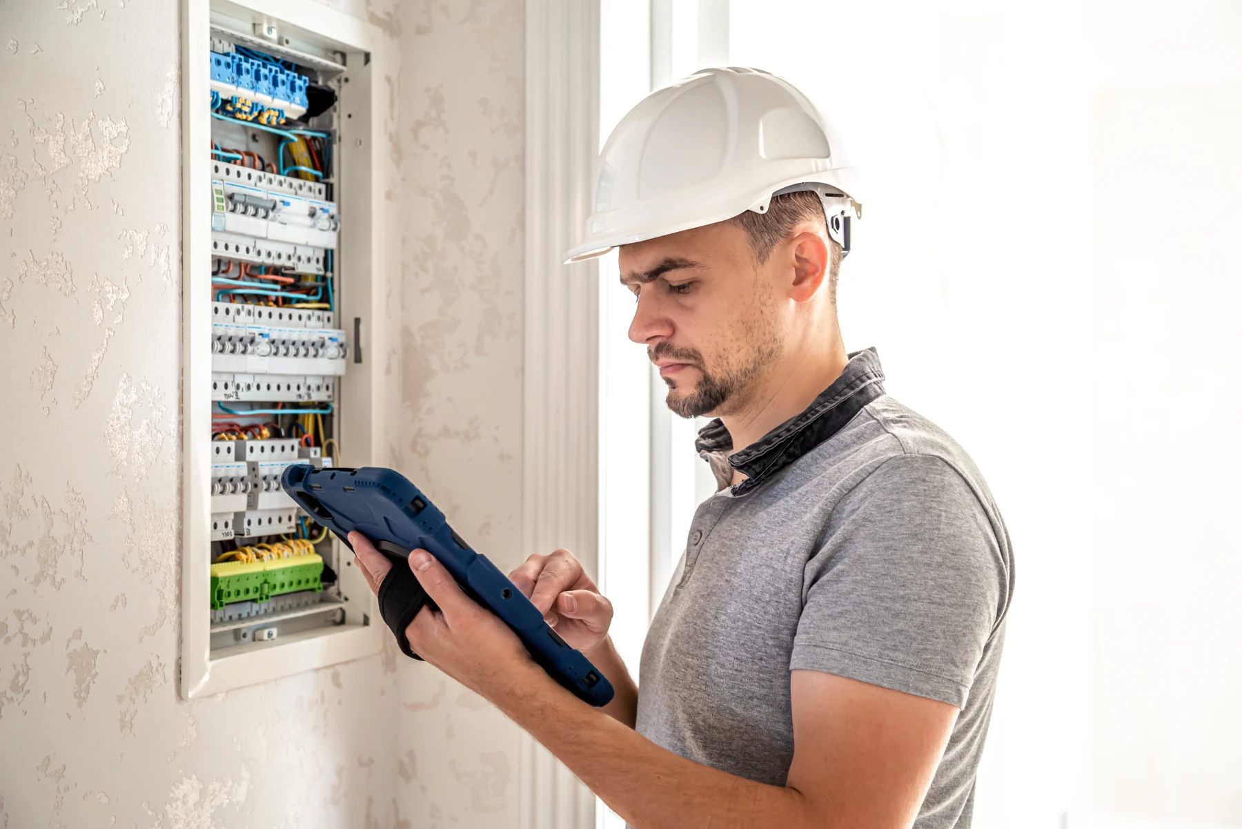 Électricien contrôlant un tableau électrique résidentiel avec un multimètre